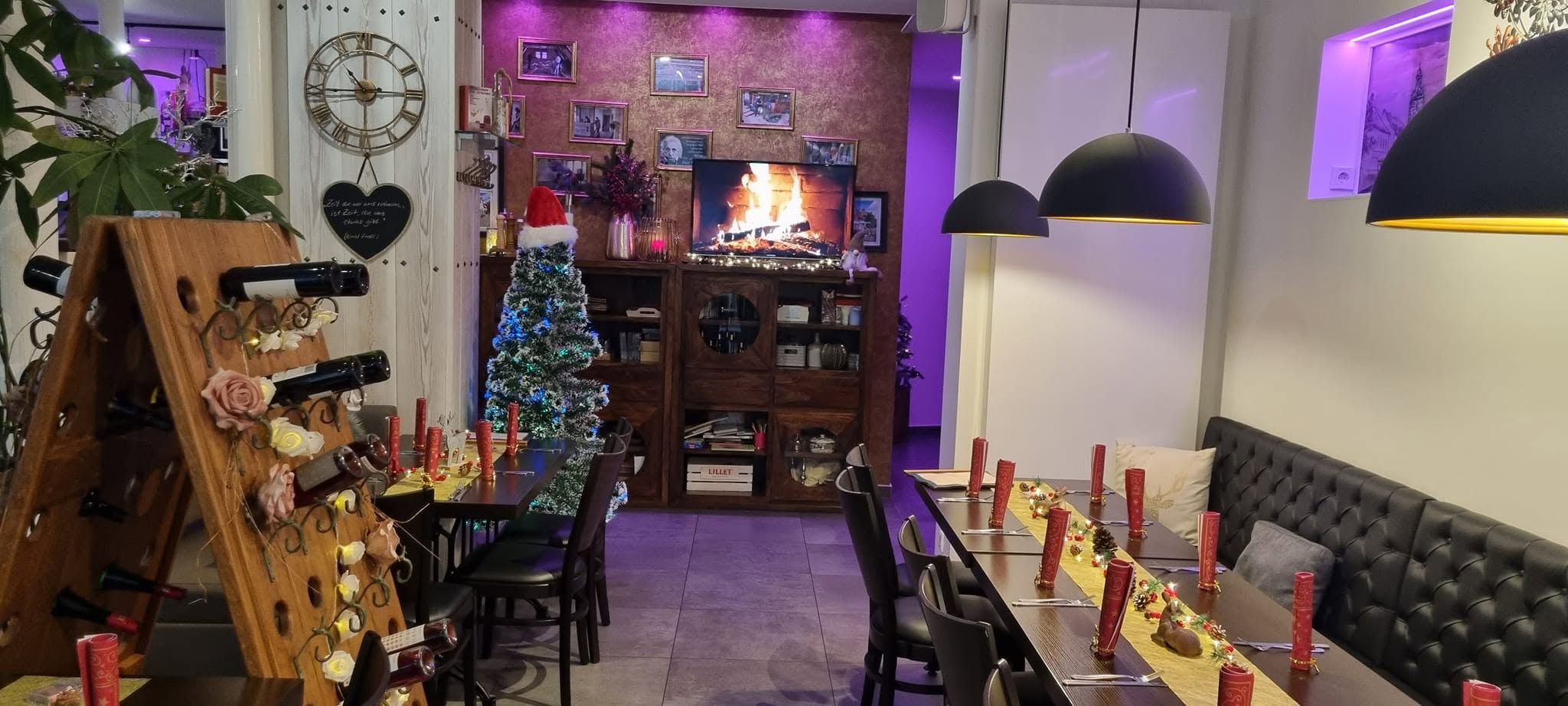 Weihnachtlich gedeckter Gastraum mit Kamin und Weinregal